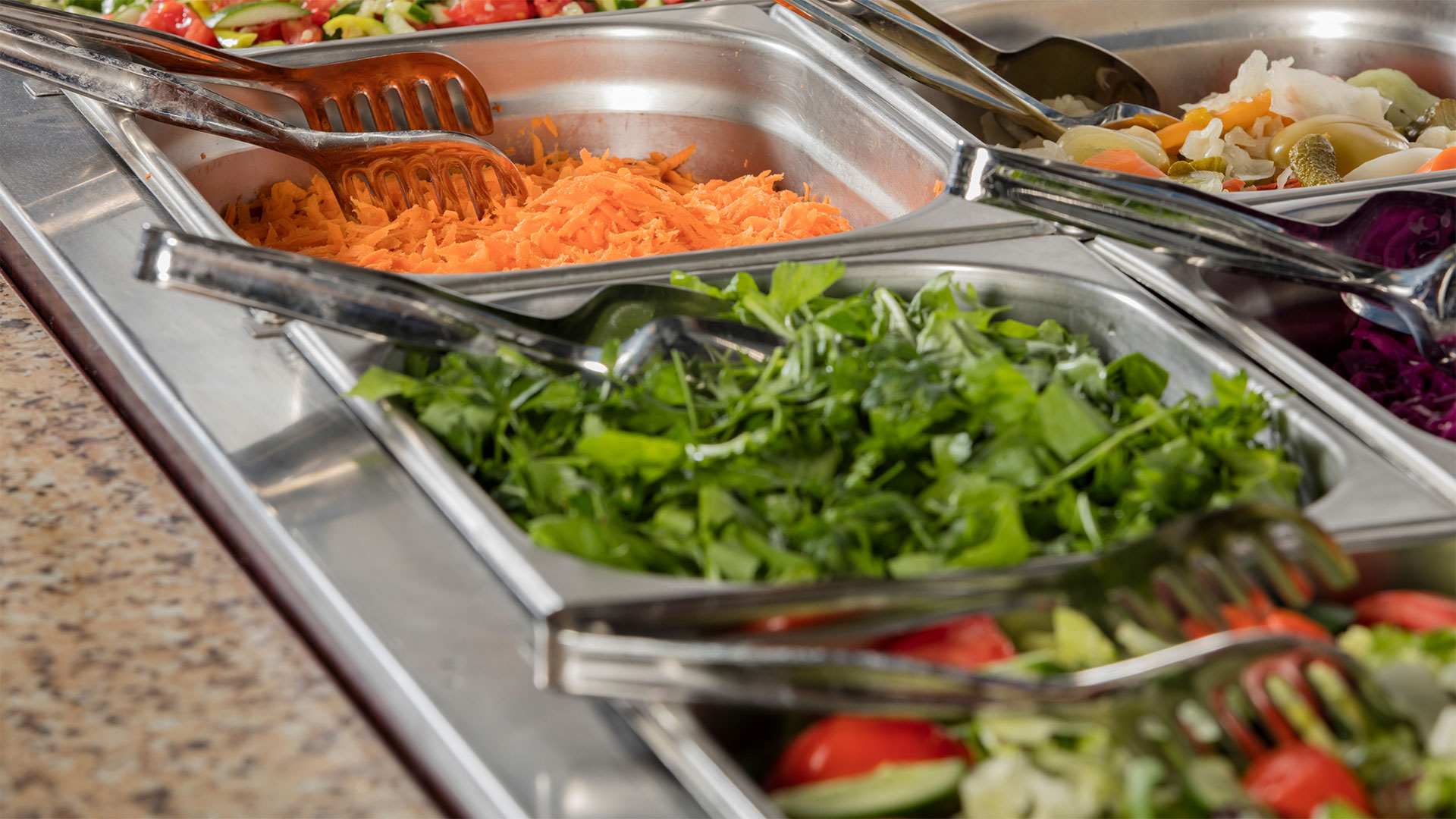 Vaschette in acciaio inox con insalate fresche e verdure pronte per il servizio di gestione mensa aziendale e ristorazione collettiva a Roma.